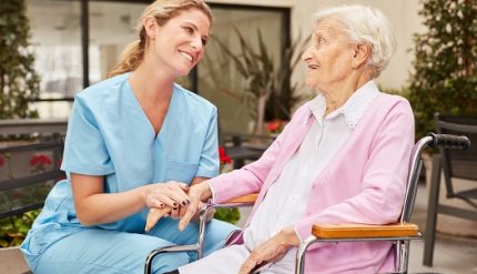 Caregiver takes care of elderly woman in wheelchair in rehab clinic or nursing home